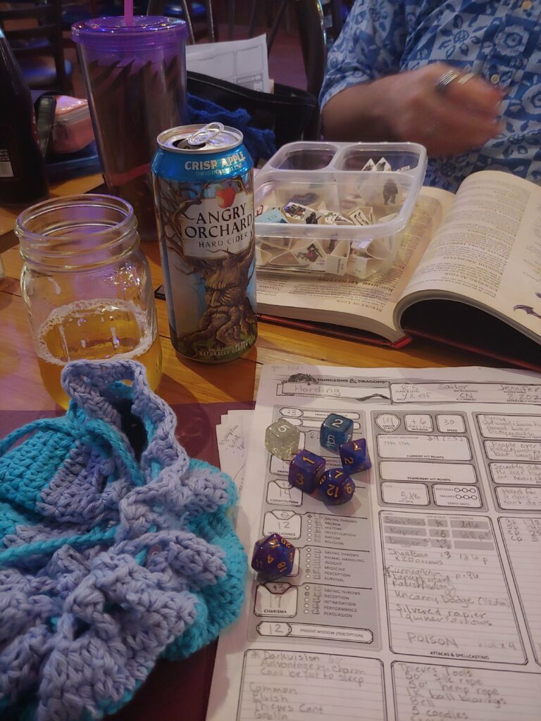 A game in progress of Dungeons and Dragons at The Bird and The Book features written notes, dice and drinks.