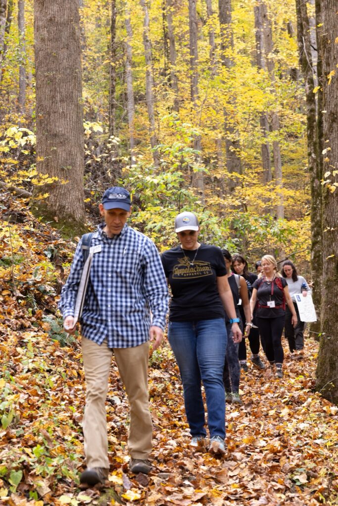 A group of people walk through autumnal forest
