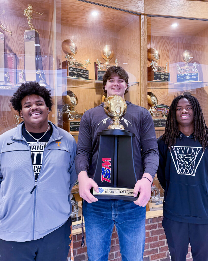 Ton'Reon Brazelton, Jacob Crow, and Jacolby Cooper hold Alcoa High School's 11th state football championship trophy.