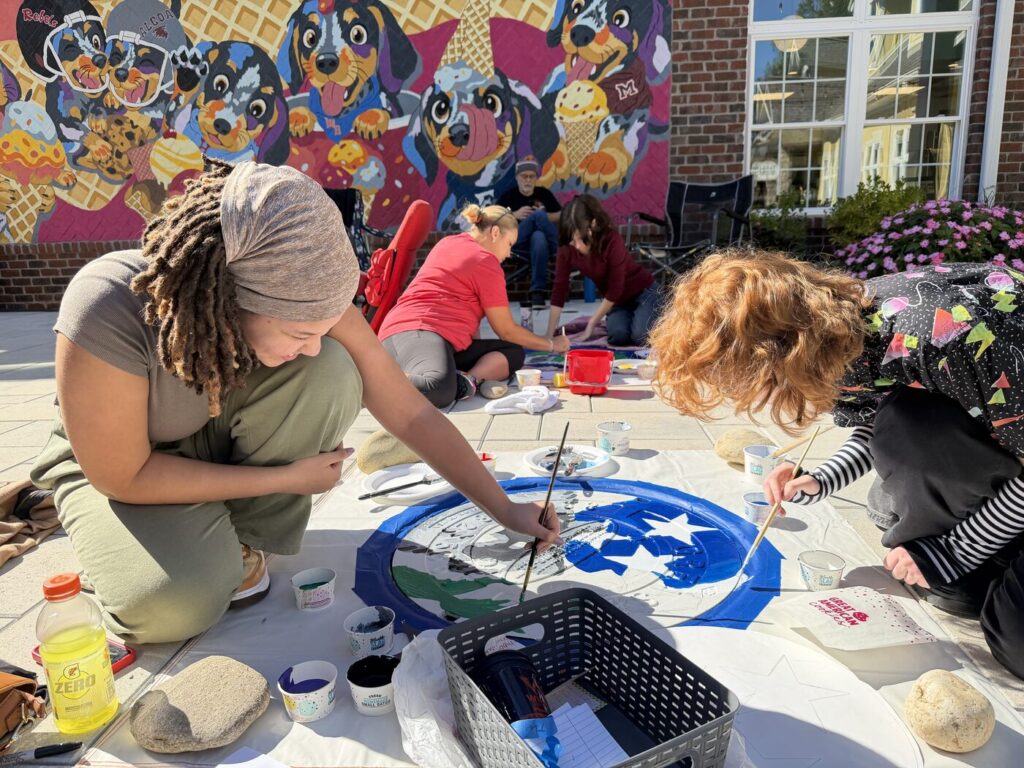 Student artists painting a manhole cover at Greenway Village in Maryville