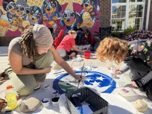 Student artists painting a manhole cover at Greenway Village in Maryville
